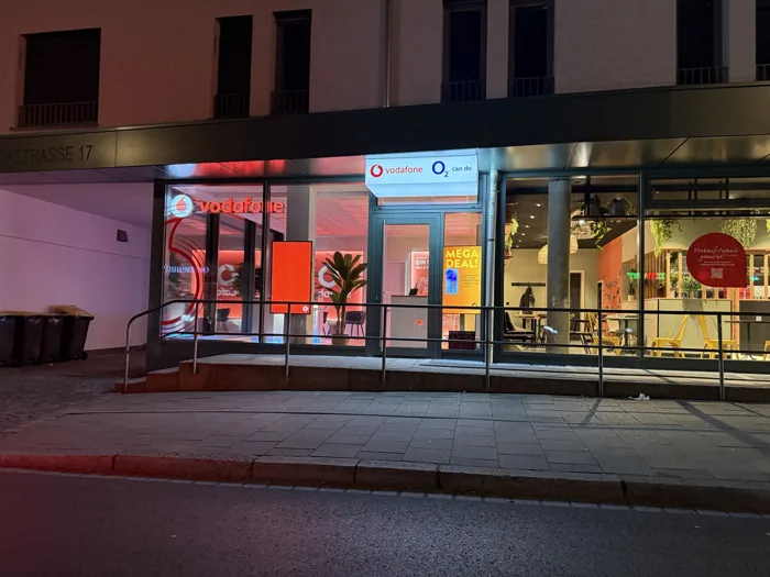 Beleuchteter Vodafone Partnershop Dachau mit Schaufenstern am Abend