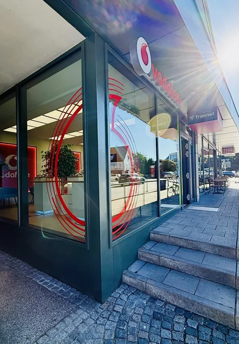 Eingang des Vodafone Partnershops Dachau mit Vodafone-Schild und Stufen bei Tageslicht